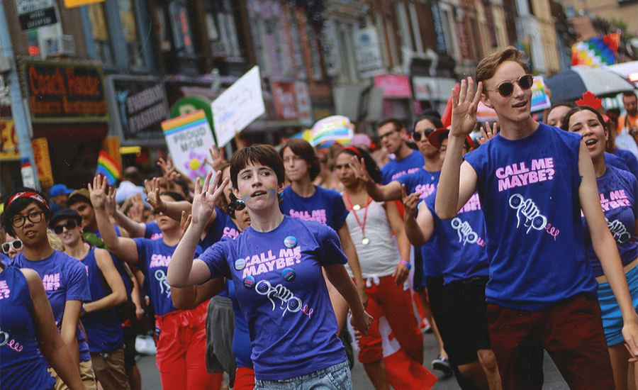 A photo of youth members marching in the Pride Parade. They are all wearing blue tshirts that read, "Call me Maybe?"