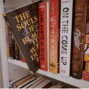 An Image Of Many Books On A Shelf. One Is Pulled Out Halfway, Titled, “The Souls Of Black Folk” By W.E.B. Du Bois.