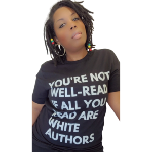 A headshot of Lalaa Comrie. She has black shoulder length hair, dark skin tone, hoop earrings, and a black shirt that reads in white text, “YOU’RE NOT WELL-READ IF ALL YOU READ ARE WHITE AUTHORS.” She is looking directly into the camera. 