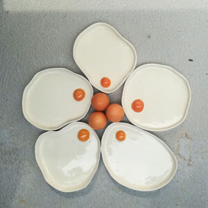 Photograph Of Five Ceramic Egg Dishes Arranged To Look Like A Flower, With Three Real Eggs In The Centre.
