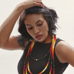 A Photo Of A Medium-dark Skinned Woman With Dark Hair Wearing Iskwew Rising's Beadwork Necklaces.