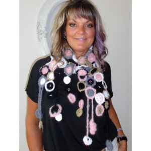 An Image Of A Woman Modelling A Crochet Scarf. The Scarf Is Made Up Of Crocheted Circles In Pink, Black, Gray And White Yarn.
