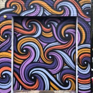 A Photo Of A Wall And Garage Door Painted With Orange And Purple Swirls And Spirals.