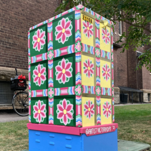 A Photo Of A Bell Box Mural Painted With Vibrant Geometric Flowers In A Colourful Grid.
