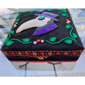 A Photo Of A Box With A Beadworked Plague Doctor And Flowers On The Top.